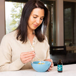 woman adding herbal cider vinegar tincture to a glass